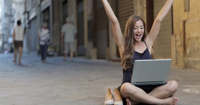 woman raising her hands up while sitting on floor with macbook pro on lap