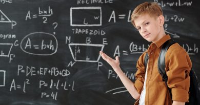 boy in brown jacket standing in front of chalk board
